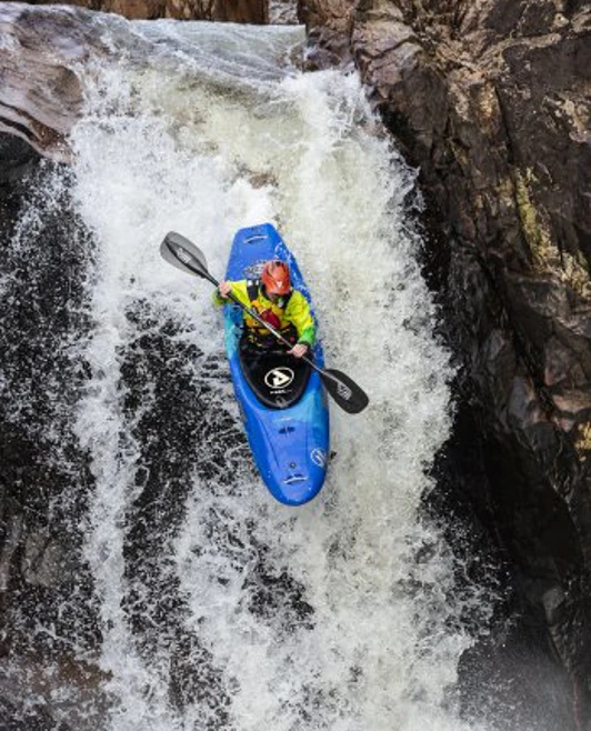 A student in a blue kayak descends a powerful waterfall during a whitewater adventure. A student in a blue kayak descends a powerful waterfall during a whitewater adventure.